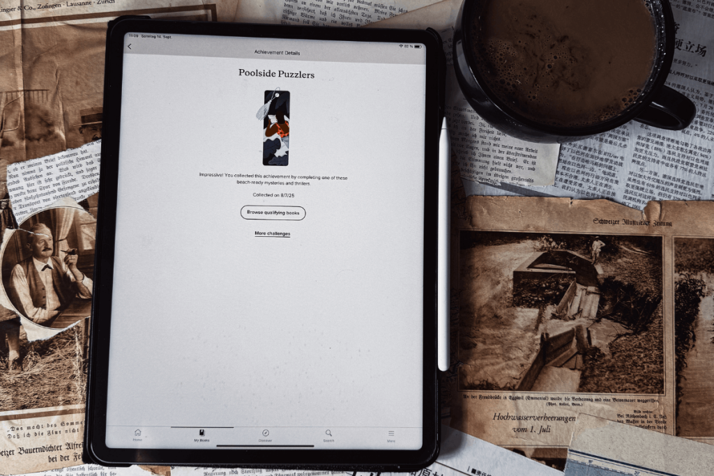 Tablet mit geöffneter Goodreads App auf der Seite eines Leseabzeichens, daneben eine Tasse Kaffee